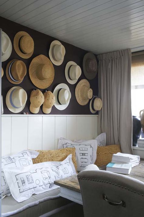 a farmhouse space with a whole wall of straw hats and baseball caps that adds eye catchiness to the space and makes it warm and cool