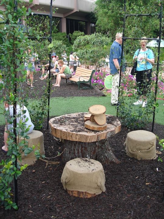 a small and pretty rustic dining space with a large tree stump and a slice on top as a table and smaller stumps as seatings