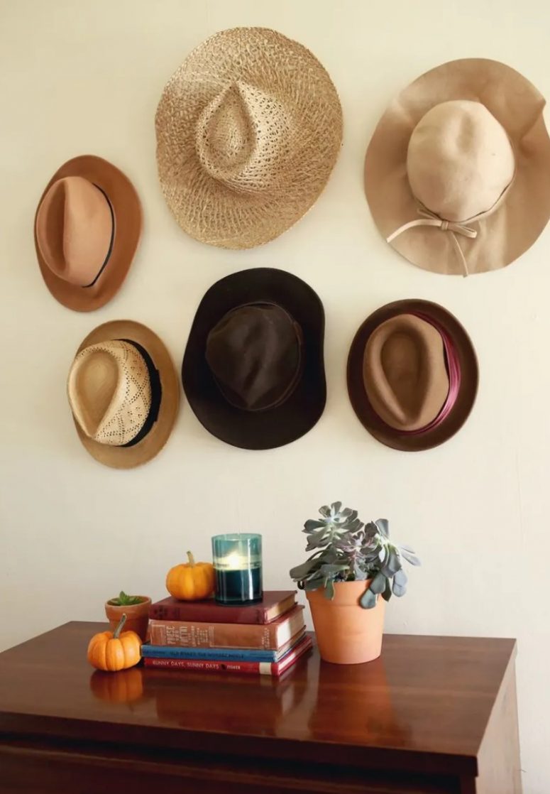a hat gallery wall composed of hooks and pretty hats hanging on them is a lovely idea for a boho or rustic space