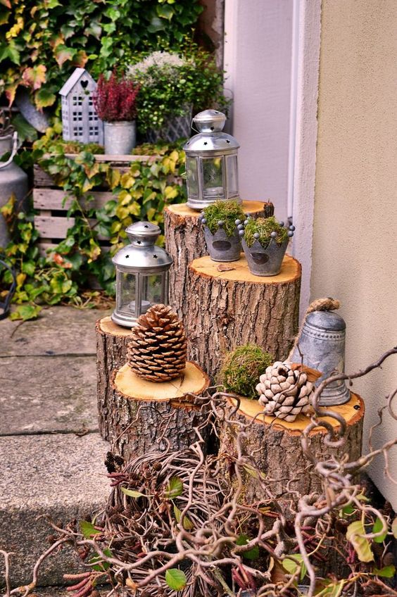 outdoor decor with tree stumps and large pinecones, candle lanterns and buckets with moss and berries is a cool and cozy idea