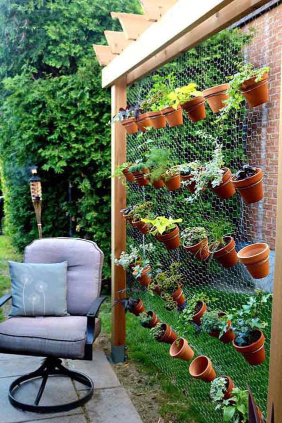 a cool and easy vertical garden composed of wood and chicken wire, with terracotta plants with herbs is a cool way to get a kitchen garden without sacrificing much space