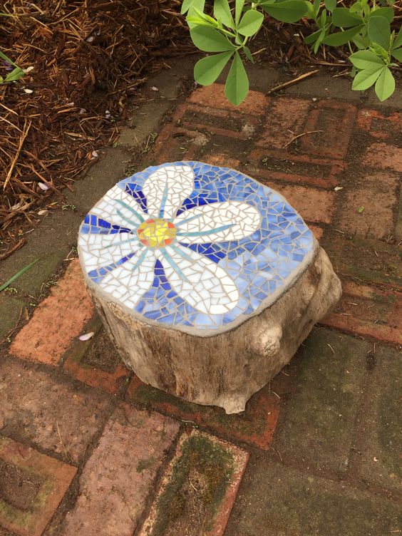 a lovely garden decoration of a tree stump with a mosaic top is an amazing idea for adding a bright touch to the space
