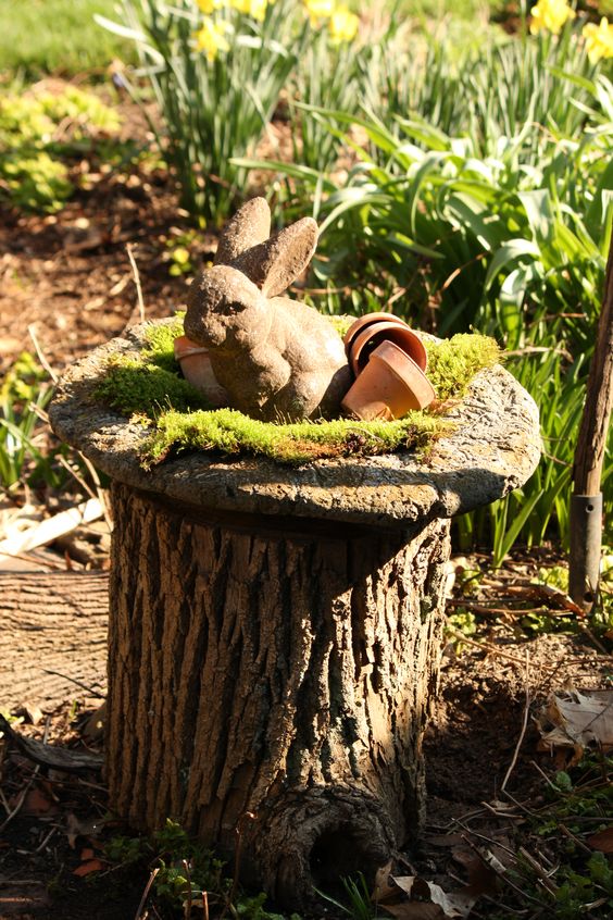 a lovely rustic decoration of a tree stump with a wood slice, moss, a bunny figure and some terracotta planters is cute and easy to repeat