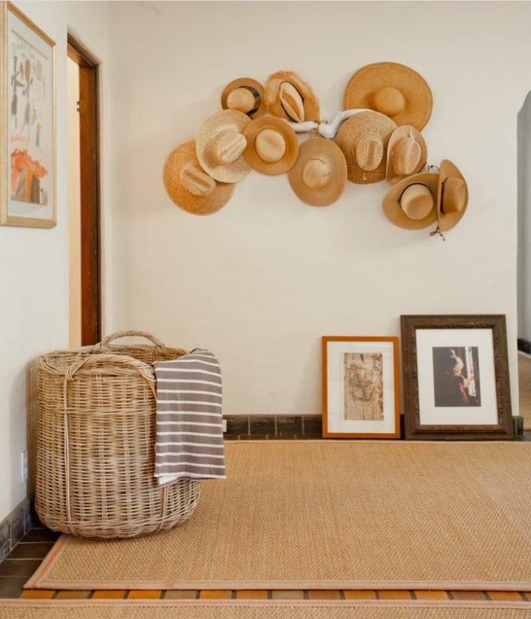 a whitewashed branch with hats attached to it, with ropes and pins is a beautiful arrangement for an entryway, great to add a Mediterranean touch to the space