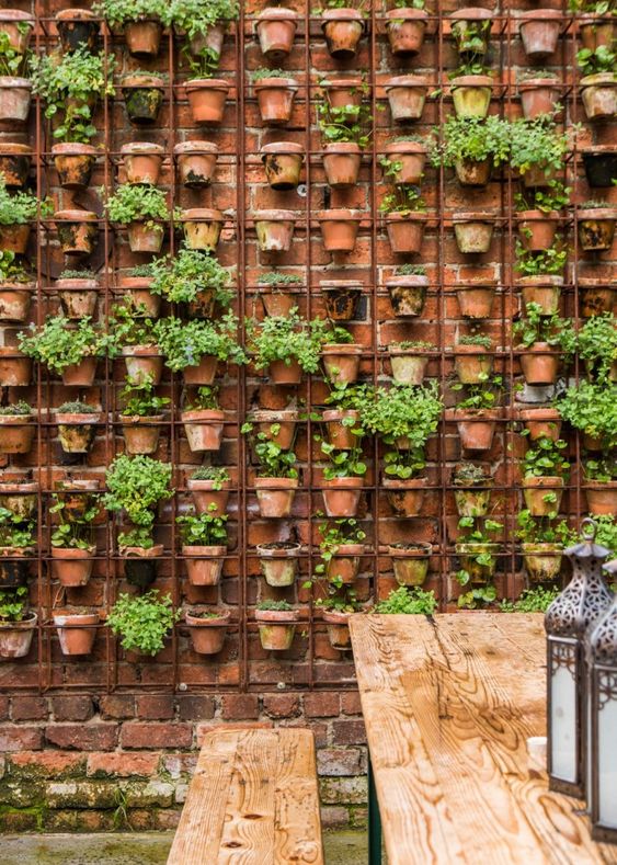 a red brick fence completely covered with a matching metal grid and terracotta planters with greenery to refresh the space