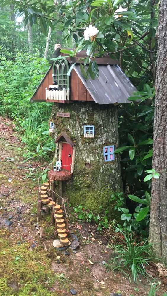 a tall tree stump with windows, a red door, a ladder of little wood slices and a large roof with a balcony is a fun gnome house
