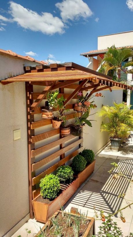 a simple and smart vertical garden of wood, with planters down and some additional planters attached to the planks above, plus a roof to hide the plants from excessive sunshine