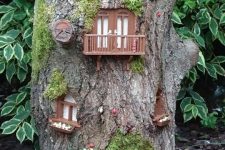 18 a tree stump turned into a whimsy decoration with windows and doors, with moss and blooms is a peculiar piece for a garden