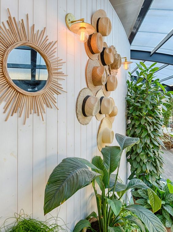 an outdoor wall decorated with straw hats that are attached to the wall and that give a light and airy feeling to the space