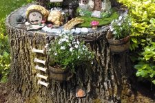 20 a lovely and cute garden decoration made of a tree stump, a little elf house, some blooms and greenery and more tiny figurines