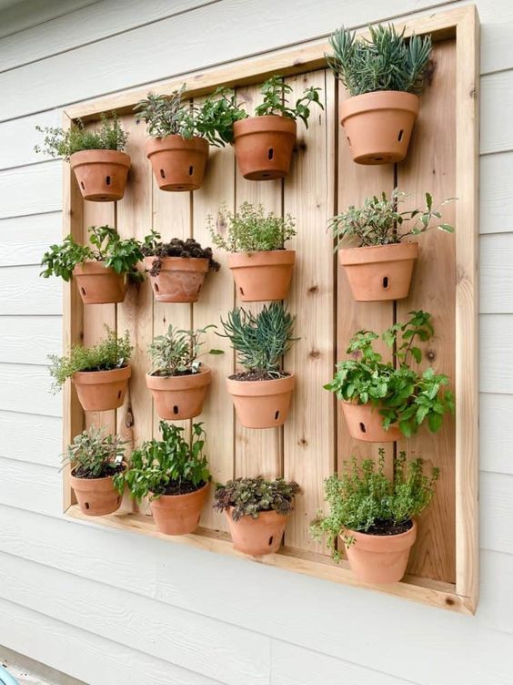 a stained wooden pallet with lots of terracotta planters and herbs is a lovely idea for a rustic space