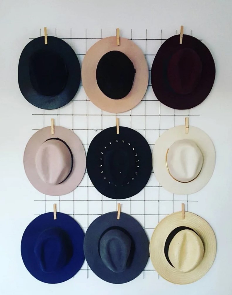 a grid with hats attached to it with clothespins is a cool and pretty idea for any space with modern or Scandi design
