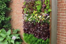 26 a wall-mounted vertical garden of wood and metal, with lots of blooms and herbs is a lovely idea for a small outdoor area