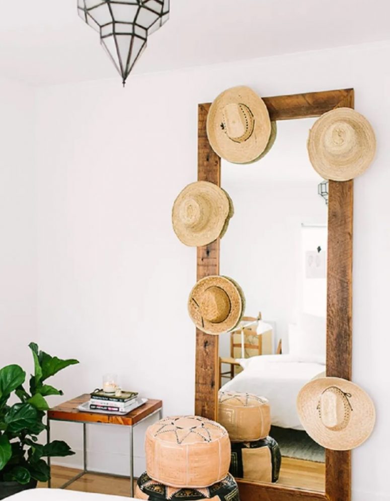 a mirror with a large stained and reclaimed wood frame with hooks and holders where you place your hats to decorate it and display them
