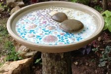 27 a tree stump holding a beautiful mosaic bird bath with seashells and pebbles is a lovely idea for any garden