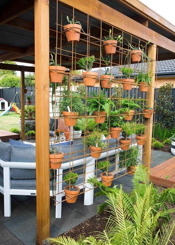 add a metal grid with terracotta plants to your outdoor space and you will get a space divider and a herb garden in one