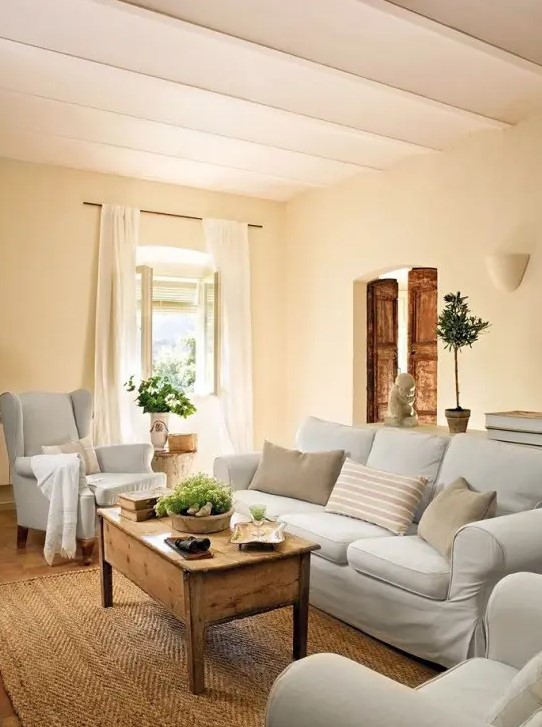 a farmhouse chic living room with neutral furniture, a jute rug and a low coffee table of stained wood