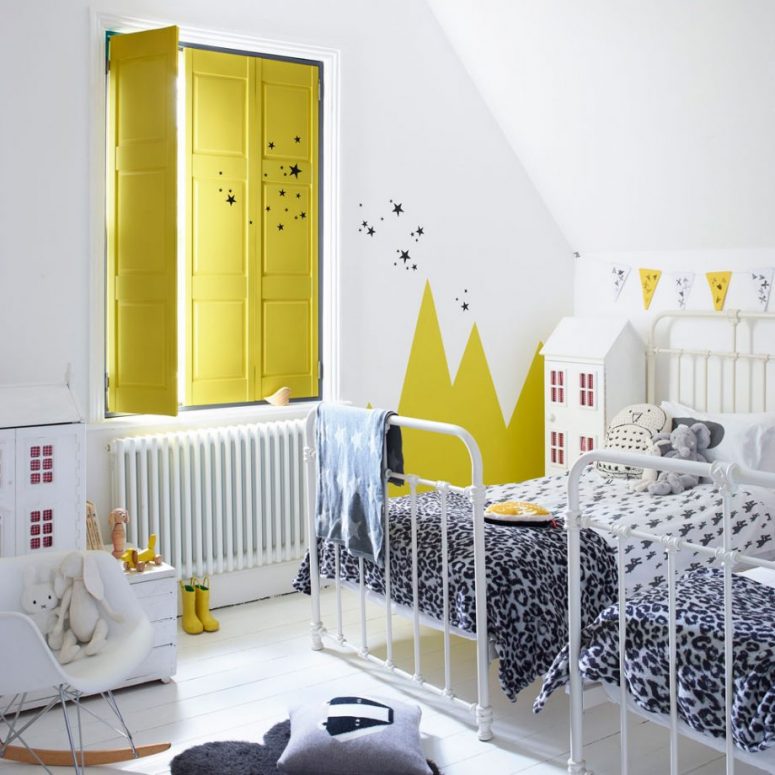a lovely bright shared kids' room with wall murals, white metal beds, printed bedding, doll houses and toys and amazing yellow solid shutters to block all the sunlight