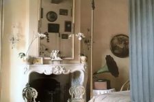 a refined French countryside bedroom with plaster walls, an antique fireplace, a large mirror, a bed with a canopy, chic carved chairs and vintage decor