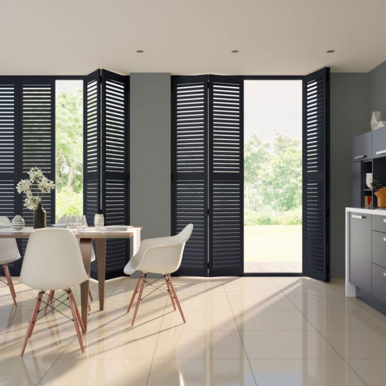 a stylish contemporary dining space done with tiles, grey walls, lightweight furniture, black shutter doors is a lovely space for meals and not only