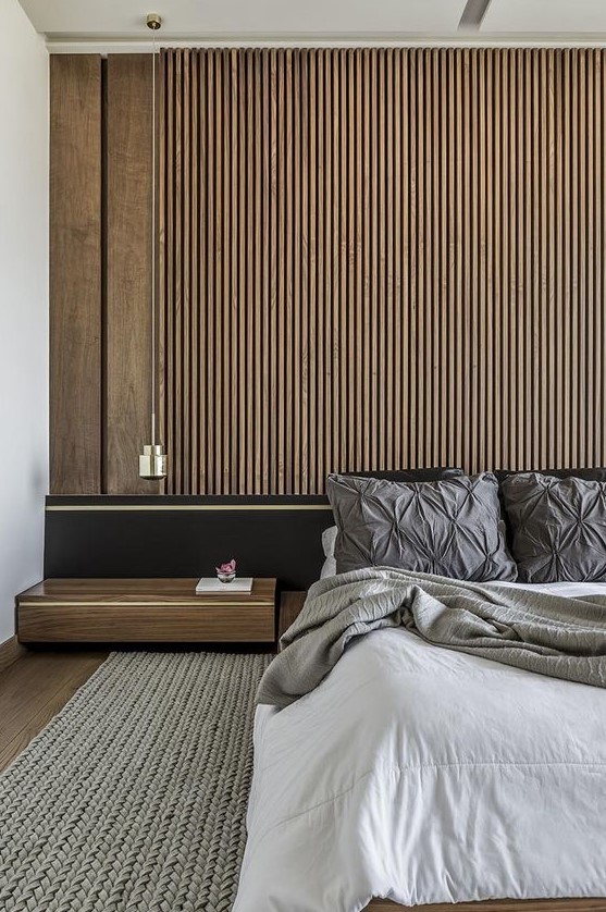 a contemporary bedroom with a wood slat accent wall, a black bed with extended headboard, neutral bedding and a floating nightstand