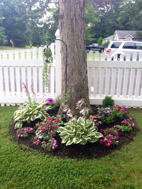 a tree surrounded with bold blooms and catchy greenery, with an additional planter on the hook is amazing