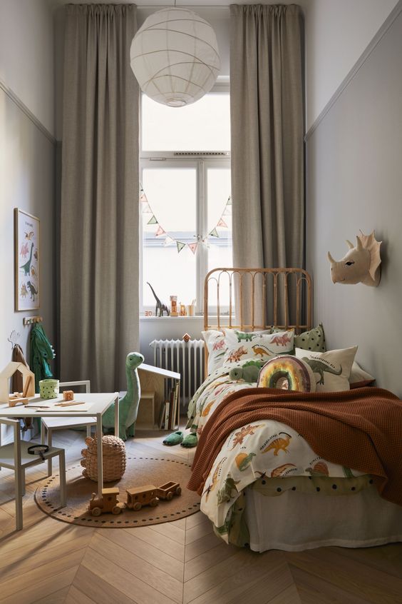 a lovely kids' room with grey walls, a metal bed and printed bedding, a desk and white chairs, some lovely toys and art
