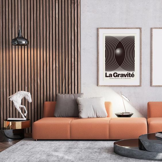 a contemporary living room with a wood slat accent wall, an orange sofa with neutral pillows and some elegant tables