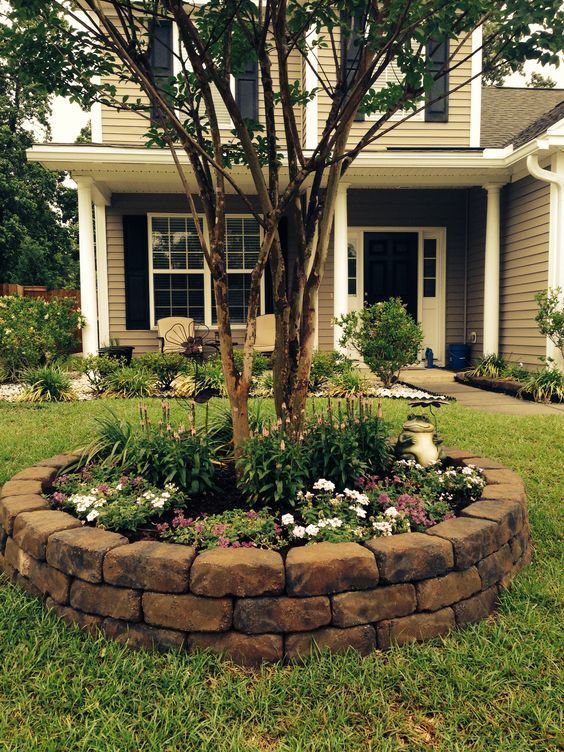 a stylish raised garden bed around the tree with pink and white blooms and greenery is a cool solution for both front and back yards
