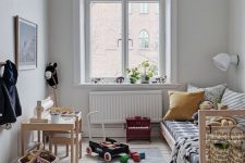 11 a Scandinavian kid’s room with a stained bed and printed bedding, a stained desk and chair, baskets and a pendant lamp