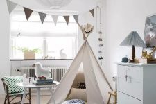a serene Scandinavian kid’s room with a bunting, a teepee, a dresser, some wooden furniture, a bed and some cute toys
