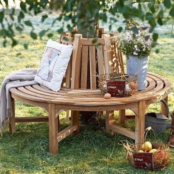 a classic wooden wrap around bench for a tree, with blankets, pillows and wire baskets is a lovely rustic decor idea