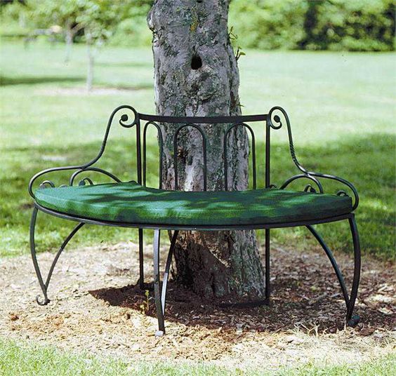 a refined curved bench of metal covering the tree partly is a chic and beautiful seat fr your garden, a green cushions makes sitting more comfortable
