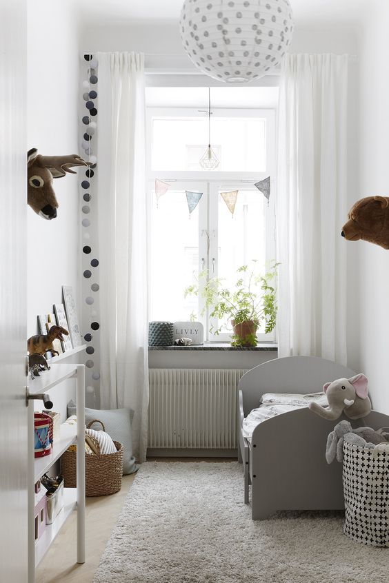 a small and cute kid's room with a grey bed, an open storage unit, polka dots for an accent and baskets
