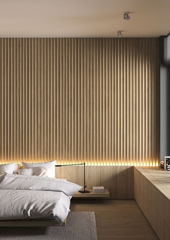 a minimalist bedroom with a light-stained wood slat accent wall, a floating bed and nightstand, a built-in windowsill storage unit