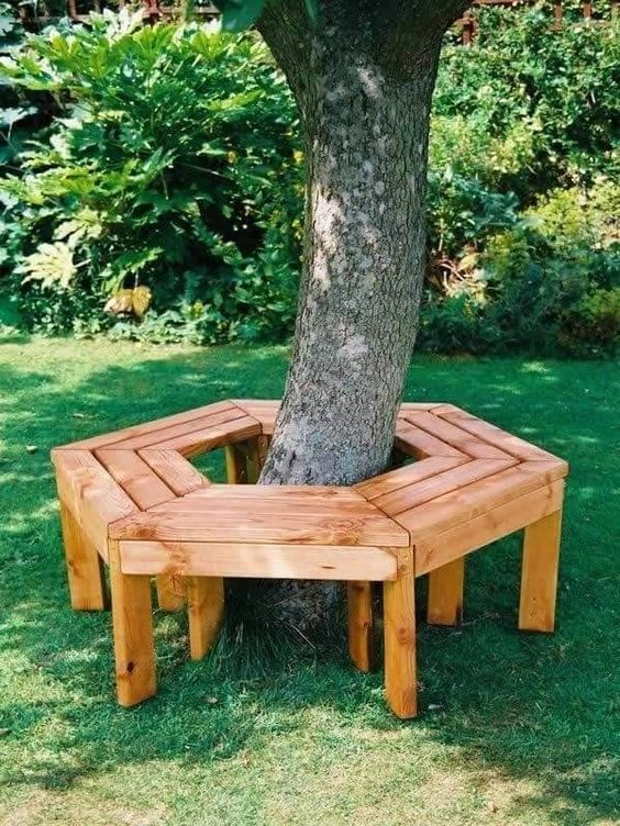 a simple stained hexagon garden bench around the tree is a cool idea for a modern to rustic garden, add pillows and blankets and enjoy