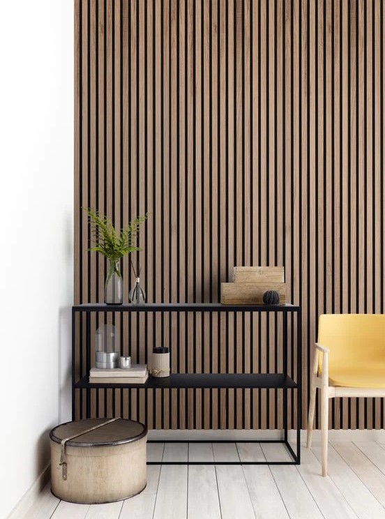 a minimalist space with a wooden slat accent wall, a black shelving unit, a yellow chair and some boxes is amazing
