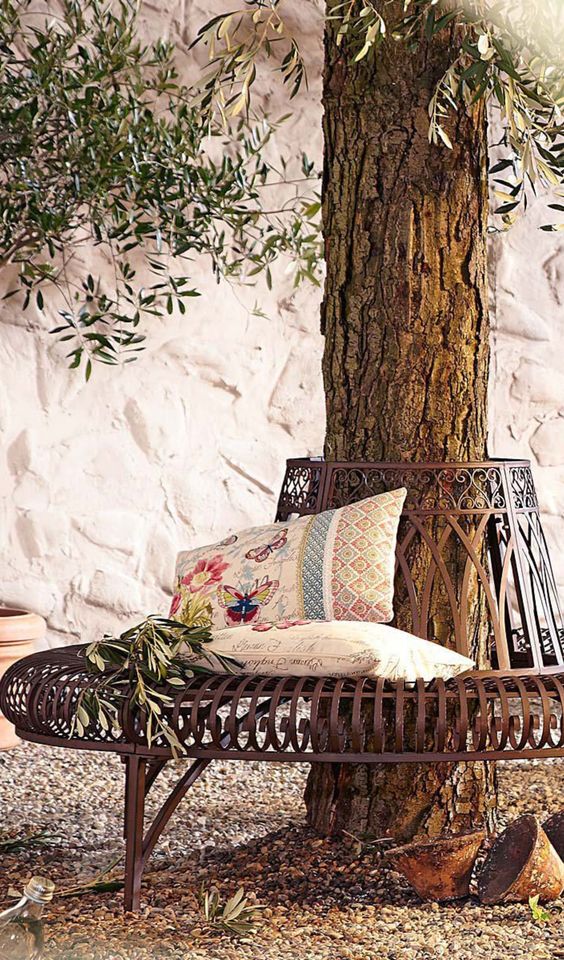 a sophisticated and chic metal bench around the tree, with printed pillows and greenery is a lovely item to sit on