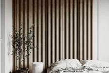 26 a neutral minimalist bedroom with a wood slat accent wall with lights over it, a low soft bed with neutral bedding and a potted tree