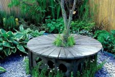 26 an elegant carved stained bench around the tree, with pebbles and blooms around is a lovely sitting spot for your garden