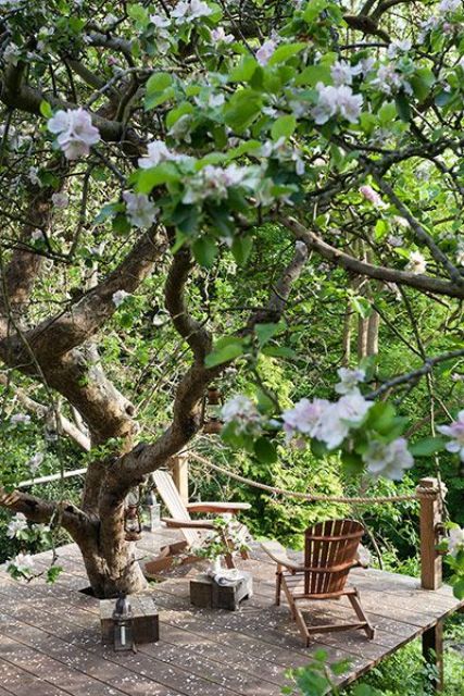 a deck around a blooming tree, with little wooden tables, wooden chairs and candle lanterns is a lovely space to spend some time