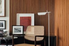 34 a mid-century modern living room with stained wood slat accent walls, a rattan chair, a black table and bright artwork