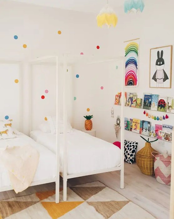 a shared kid's room done in neutrals but spruced up with brights - polka dots on the wall, colorful art, garlands and books