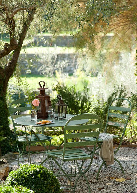 a little dining space around the tree, with a green metal dining set and some candle lanterns is an amazing idea for any garden