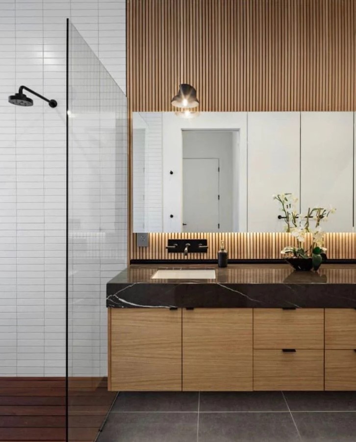 a modern bathroom with white skinny tiles, a light-stained floating vanity and a wood slat wall, a mirror and large scale tiles on the floor