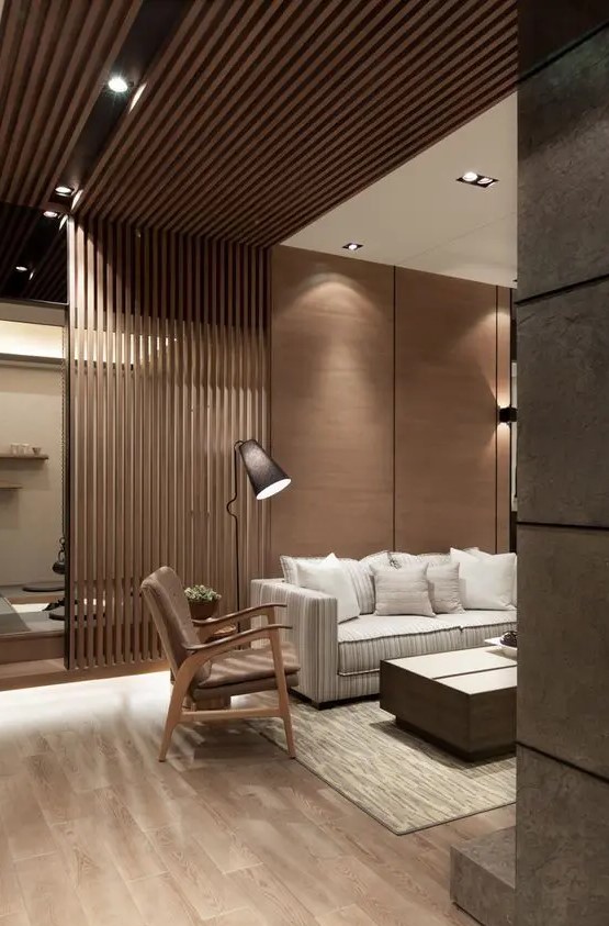 a modern living room with a wooden wall, the part of which is ofslats that create a space divider