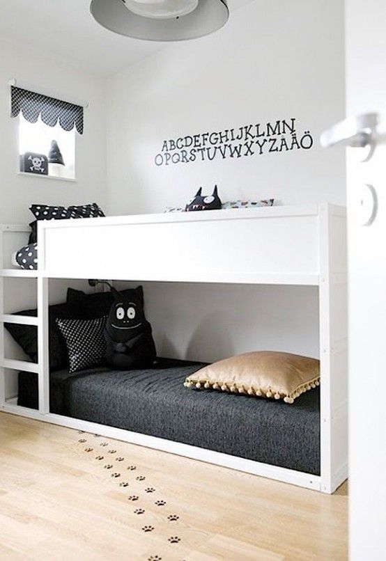 a small Scandi shared kids' room with a bunk bed and black bedding, some lovely wall and floor decor and a printed curtain