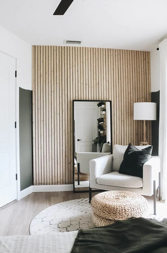 a neutral mid-century modern living room with color block walls, a wood slat accent wall, a floor mirror, a neutral chair and jute poufs
