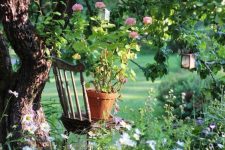 39 a vintage chair placed under the tree, with potted blooms and blooms around the treee form a cool outdoor nook