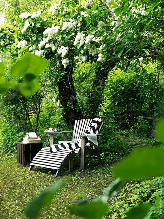 an under the tree mini lounge with a wooden lounger and a crate side table, some blankets and books is amazing